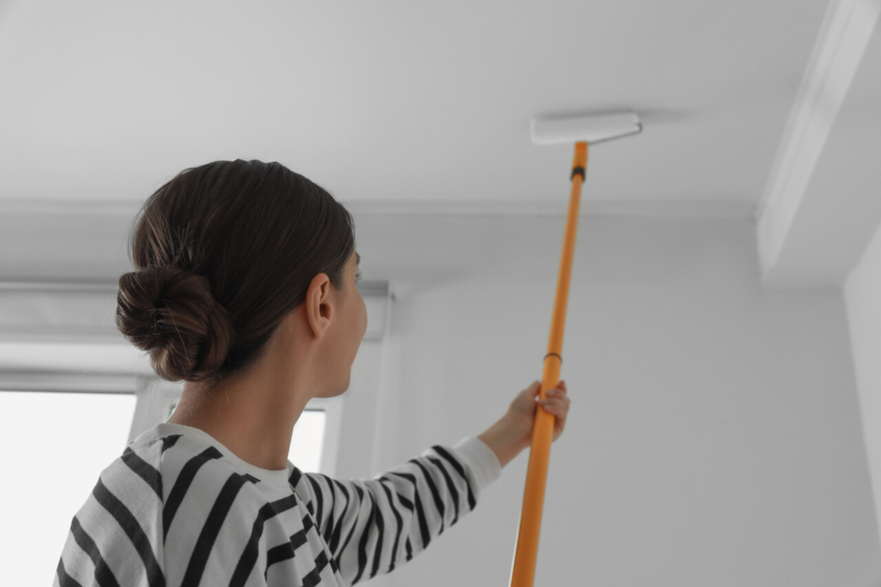 beyaz tavan boyası uygulayan kadın işçi